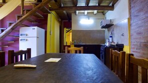 A kitchen with a wooden table, chairs, and a refrigerator. - la aldea de san rafal (San Rafael)