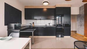 A modern kitchen with dark cabinetry, a stainless steel refrigerator, a microwave, and a coffee maker. - Dream 30 | Duży Loft z 2 Sypialniami | Bydgoszcz (Bydgoszcz)