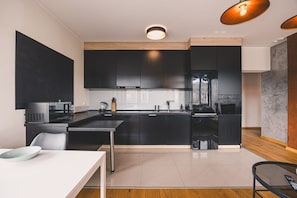 Eine moderne Küche mit dunklen Schränken, einem Edelstahlkühlschrank, einer Mikrowelle und einer Kaffeemaschine.