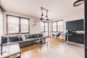 A modern living room with a grey sofa, a coffee table, and a dining area with a table and chairs. - Dream 30 | Duży Loft z 2 Sypialniami | Bydgoszcz (Bydgoszcz)