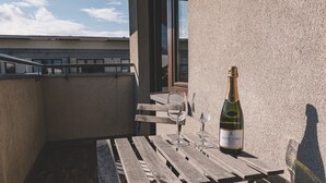 A balcony with a wooden table, a bottle of wine, and two glasses. - Dream 30 | Duży Loft z 2 Sypialniami | Bydgoszcz (Bydgoszcz)