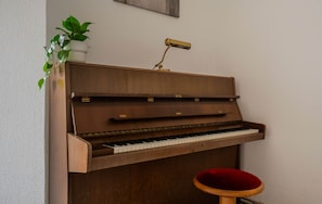 A wooden upright piano with a red stool in front. - City Apartment mit Terrasse (Worms)