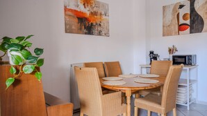 Ein Essbereich mit einem runden Holztisch, sechs Korbstühlen und einem Blumentopf.