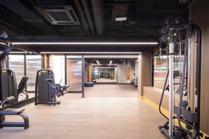 A gym with exercise equipment, a wooden floor, and a view through a glass door. - Modern London 1BR near St Pancras - StayCozy (London)