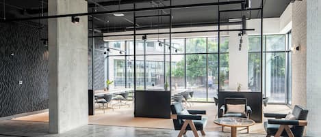 Un interior moderno con techo alto, conductos expuestos y ventanas amplias que ofrecen vistas al exterior.