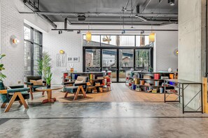 A modern interior with exposed brick walls, large windows, and a central seating area with bookshelves. - Modern London 1BR near St Pancras - StayCozy (London)