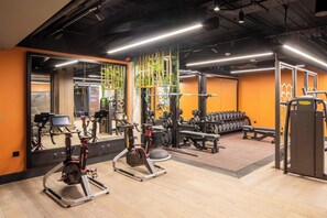Ett gym med konditionsmaskiner, styrketräningsutrustning och speglar.