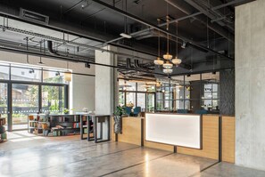 A modern office space with a reception desk, bookshelves, and large windows. - Modern London 1BR near St Pancras - StayCozy (London)