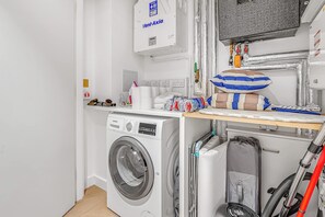 A laundry room with a Siemens washing machine, a Vent-Axia dryer, and a vacuum cleaner. - Modern London 1BR near St Pancras - StayCozy (London)