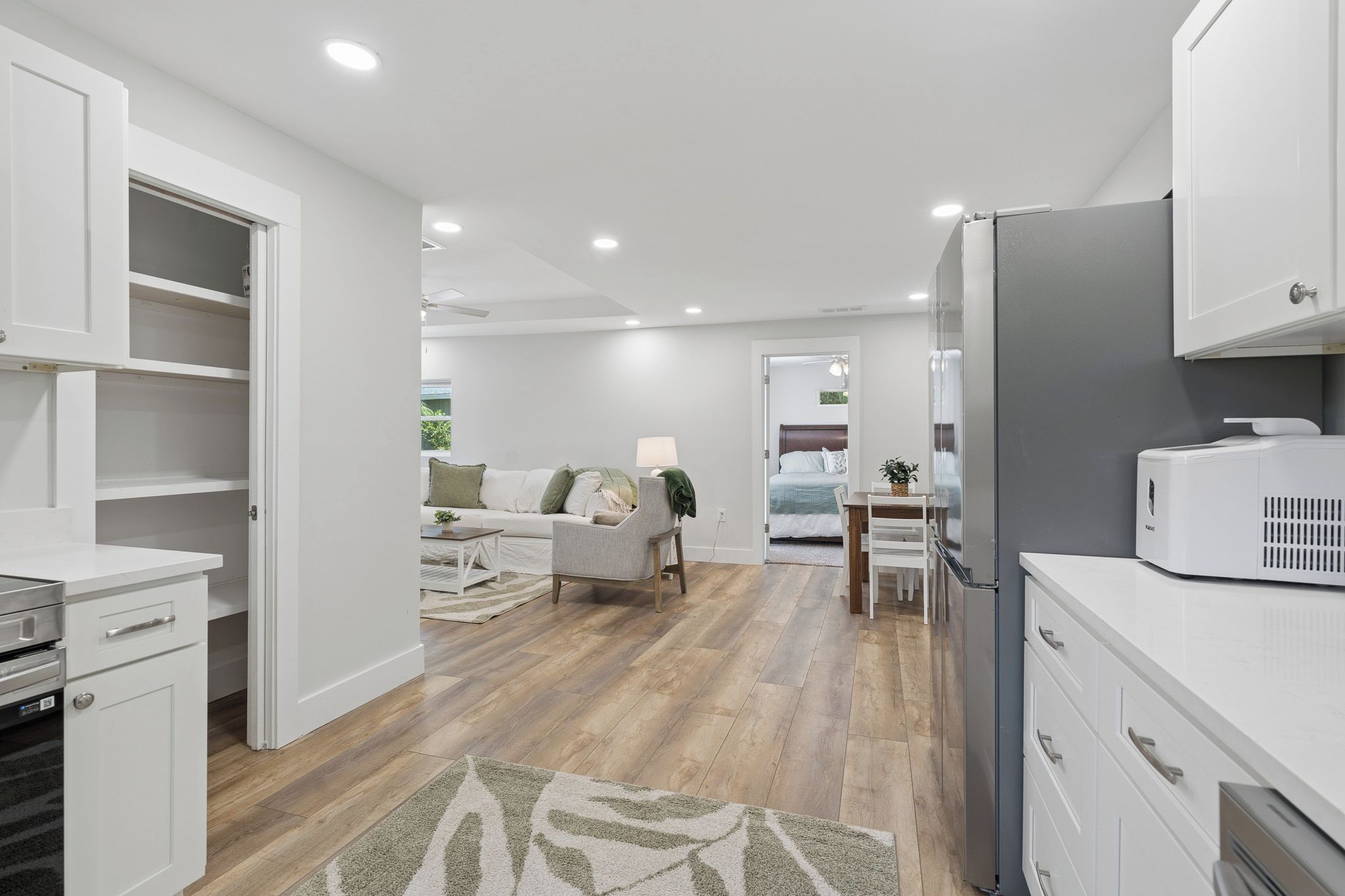 A modern kitchen with white cabinetry, a built-in oven, and a refrigerator.
