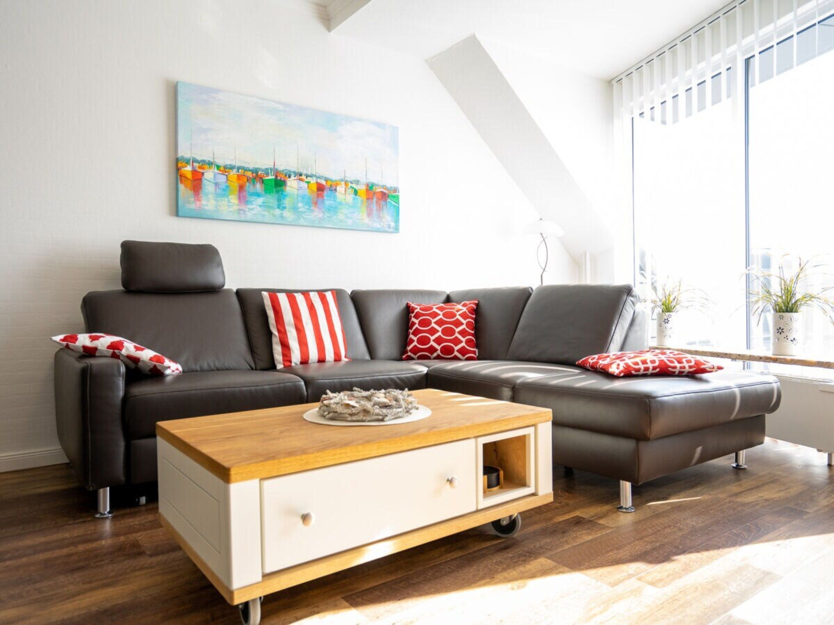 Un salon moderne avec un canapé en cuir, une table basse en bois et un tableau accroché au mur.