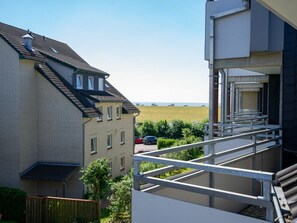 Ein Wohngebäude mit einem Balkon mit Blick auf eine Wiese.