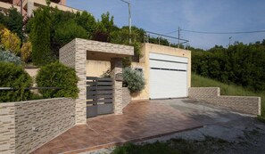A modern house with a garage, a gated entrance, and a paved driveway.