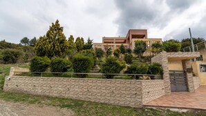 Un edificio moderno con techo plano, rodeado por un jardín ajardinado con arbustos y árboles diversos.