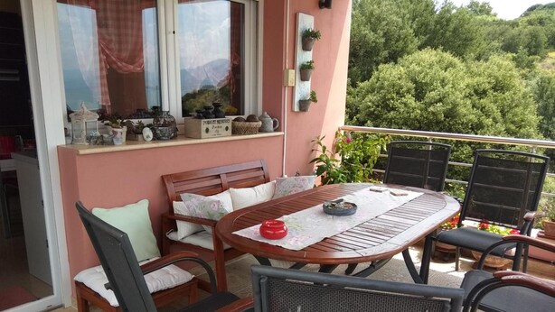 Un patio al aire libre con una mesa y sillas de madera, un sofá y una ventana con cortinas.
