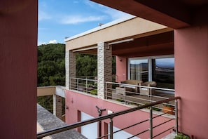 Ein modernes Gebäude mit einem Balkon, einer Glasdoor und Blick auf eine gebirgige Landschaft.