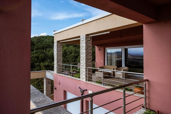 Un edificio moderno con balcón, puerta de cristal y vistas a un paisaje montañoso.