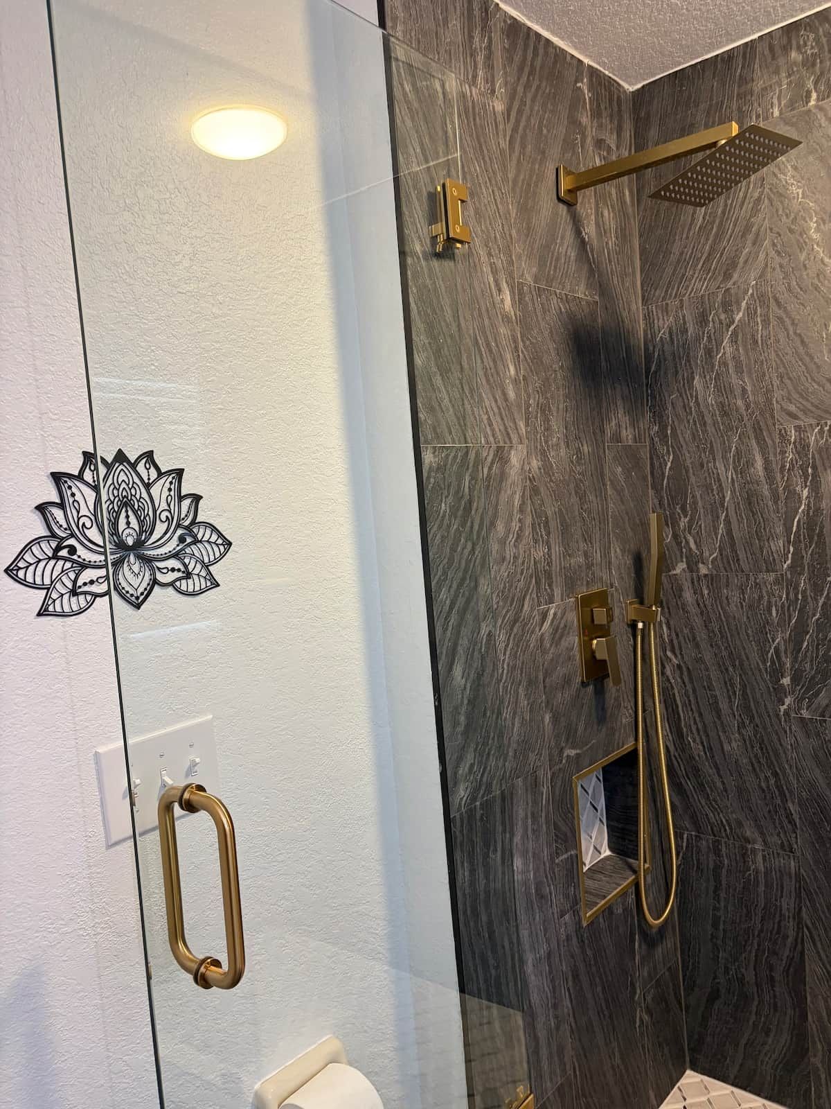 A modern bathroom with a glass partition, a lotus design, a shower with a golden showerhead, and a toilet with a golden handle.