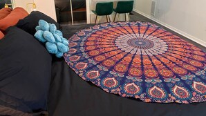 A bedroom with a large bed, a round patterned rug, and a desk with two chairs. - Paradise Goddess at Paradise Lakes Nudist Resort (Land O' Lakes)