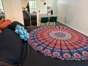 Ein Schlafzimmer mit einem großen Bett, einem runden Teppich mit Muster und einem Schreibtisch mit zwei Stühlen.