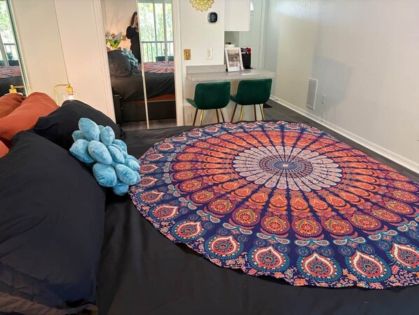 Un dormitorio con una cama grande, un tapete redondo estampado y un escritorio con dos sillas.