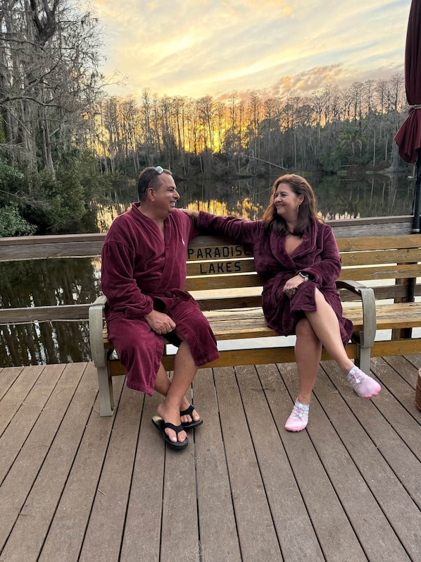 Two people sitting on a wooden bench with a sign that reads 'PARADISE LAKES' in the background.
