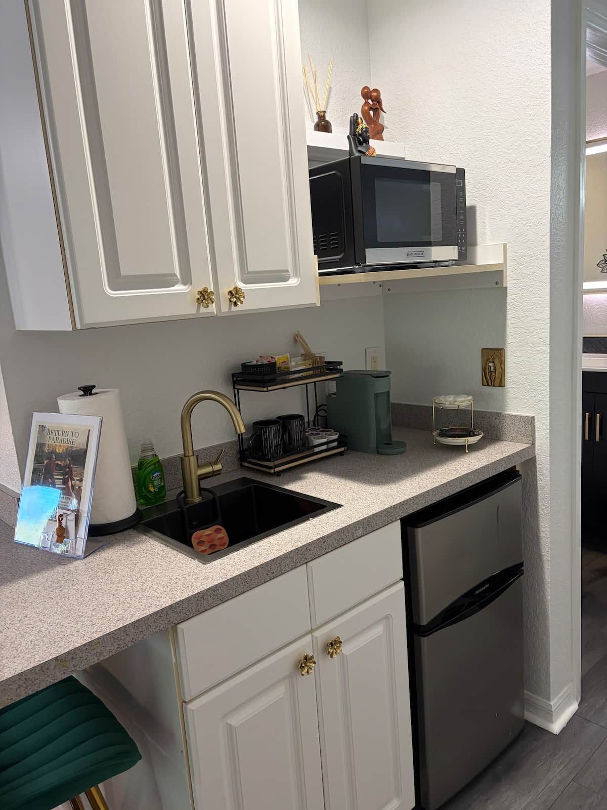 A kitchen with white cabinets, a black microwave, a sink, and a dishwasher.