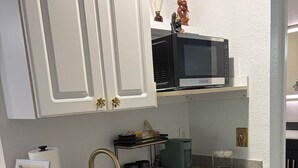 A kitchen with white cabinets, a black microwave, a sink, and a dishwasher. - Paradise Goddess at Paradise Lakes Nudist Resort (Land O' Lakes)