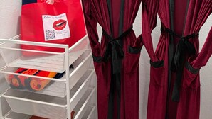A storage rack with folded clothes and a red bag with a QR code. - Paradise Goddess at Paradise Lakes Nudist Resort (Land O' Lakes)
