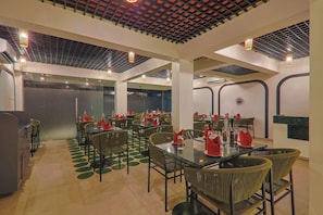 A restaurant with multiple tables and chairs, a patterned ceiling, and a modern design. - The Orchid Passaros Goa Adults Only (Benaulim)