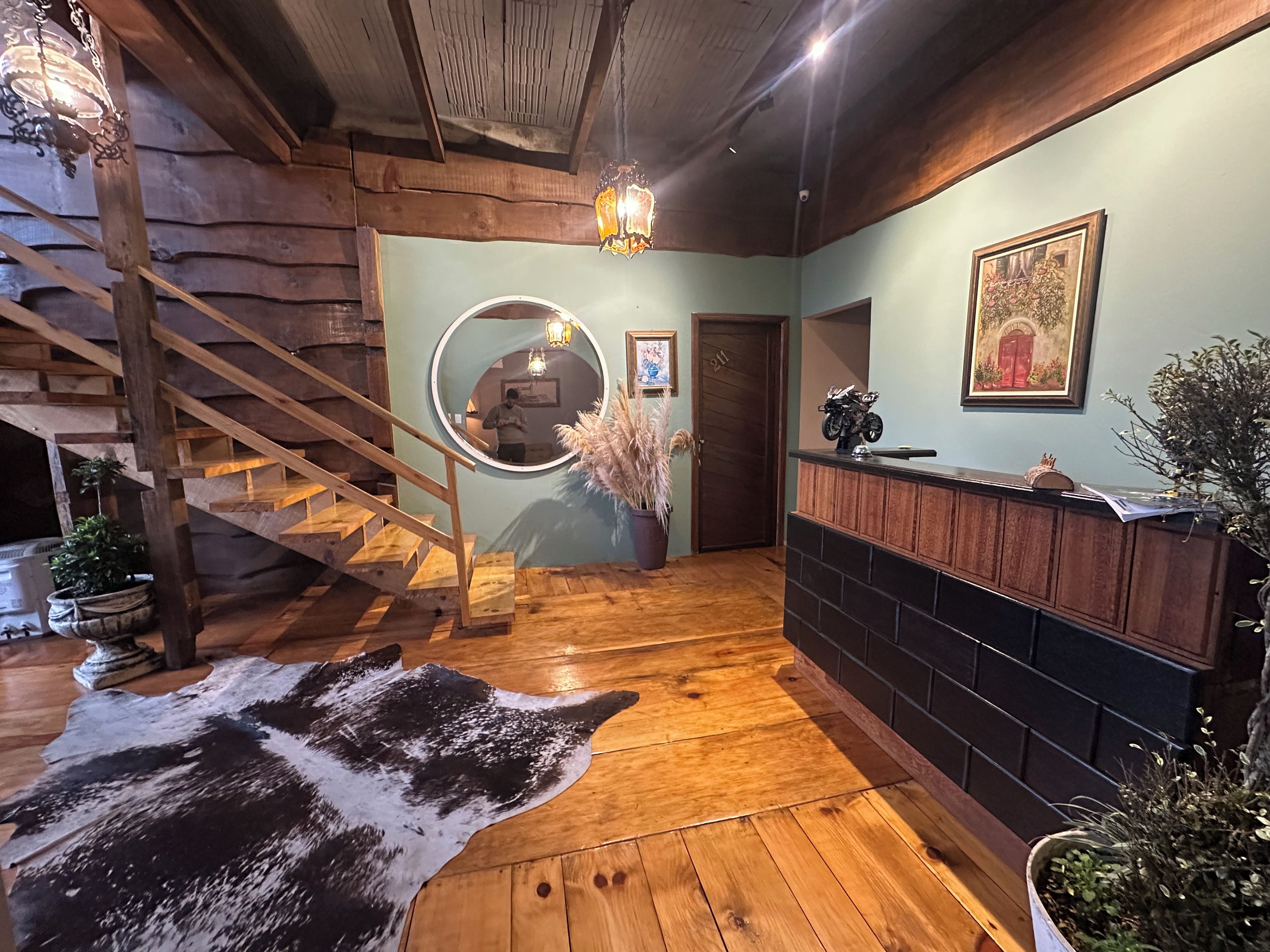Una escalera de madera, una recepción y un espejo circular.