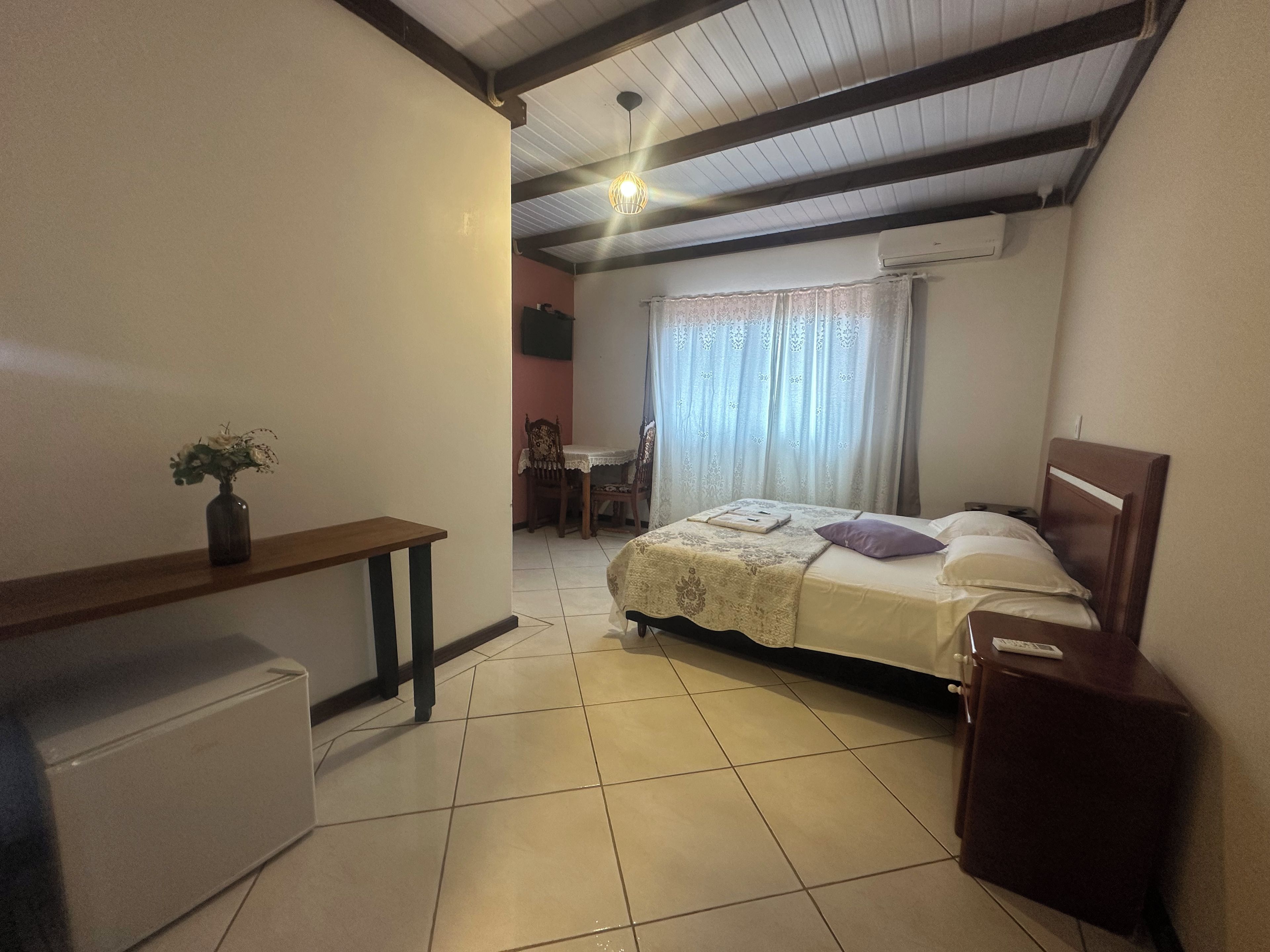 A bedroom with a bed, bedside table, and a small desk with a chair.
