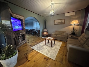 A cozy living room with a fireplace, wooden flooring, a sofa, a coffee table, and a television.
