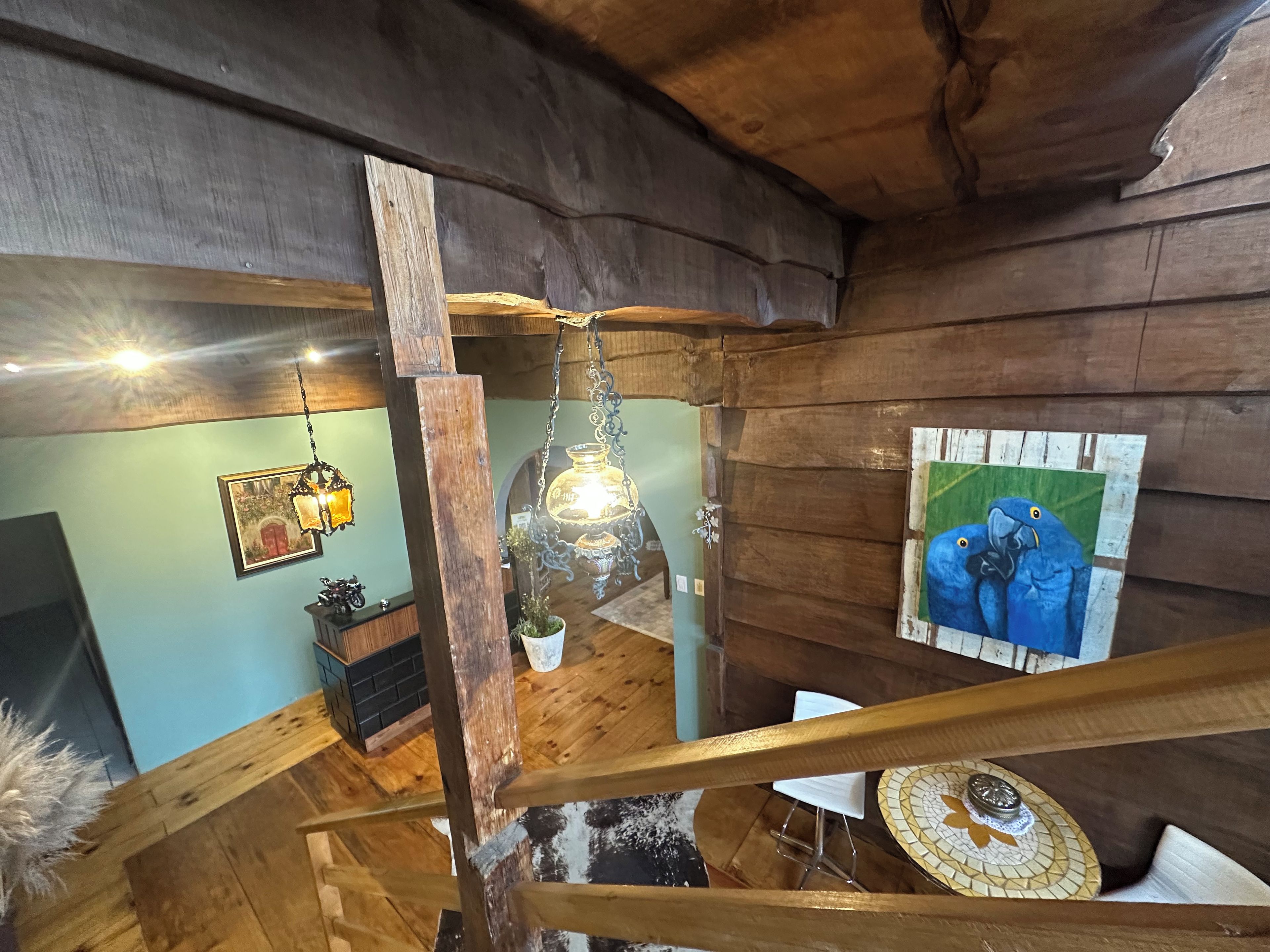 Interior de madera con una escalera, una lámpara colgante y un cuadro en la pared.