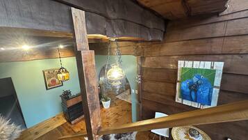 Interior de madera con una escalera, una lámpara colgante y un cuadro en la pared.