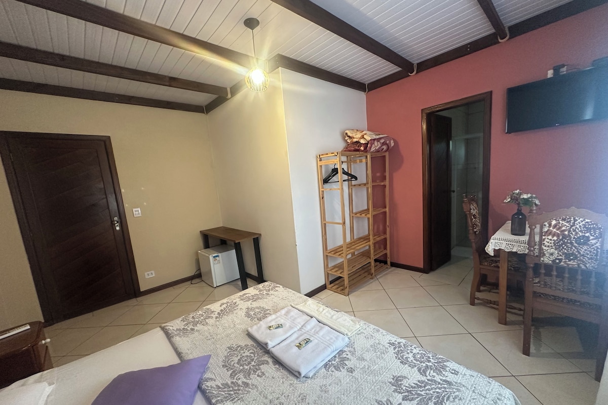 Un dormitorio con cama, armario de madera, una mesita y una silla.