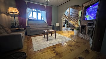 A living room with a sofa, armchair, coffee table, and a television.