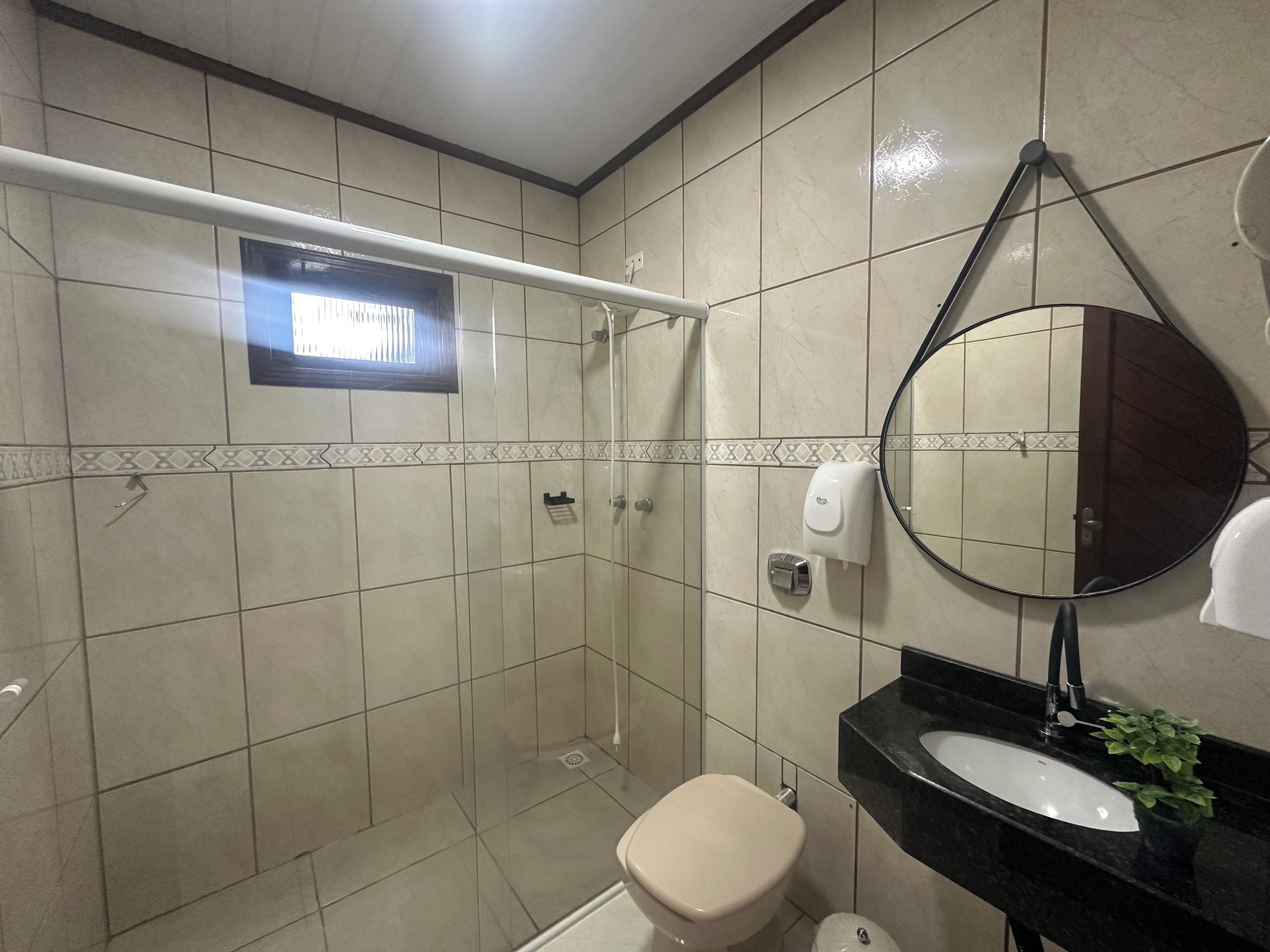 A bathroom with a shower, toilet, sink, and a mirror.