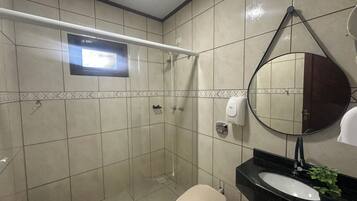 A bathroom with a shower, toilet, sink, and a mirror.