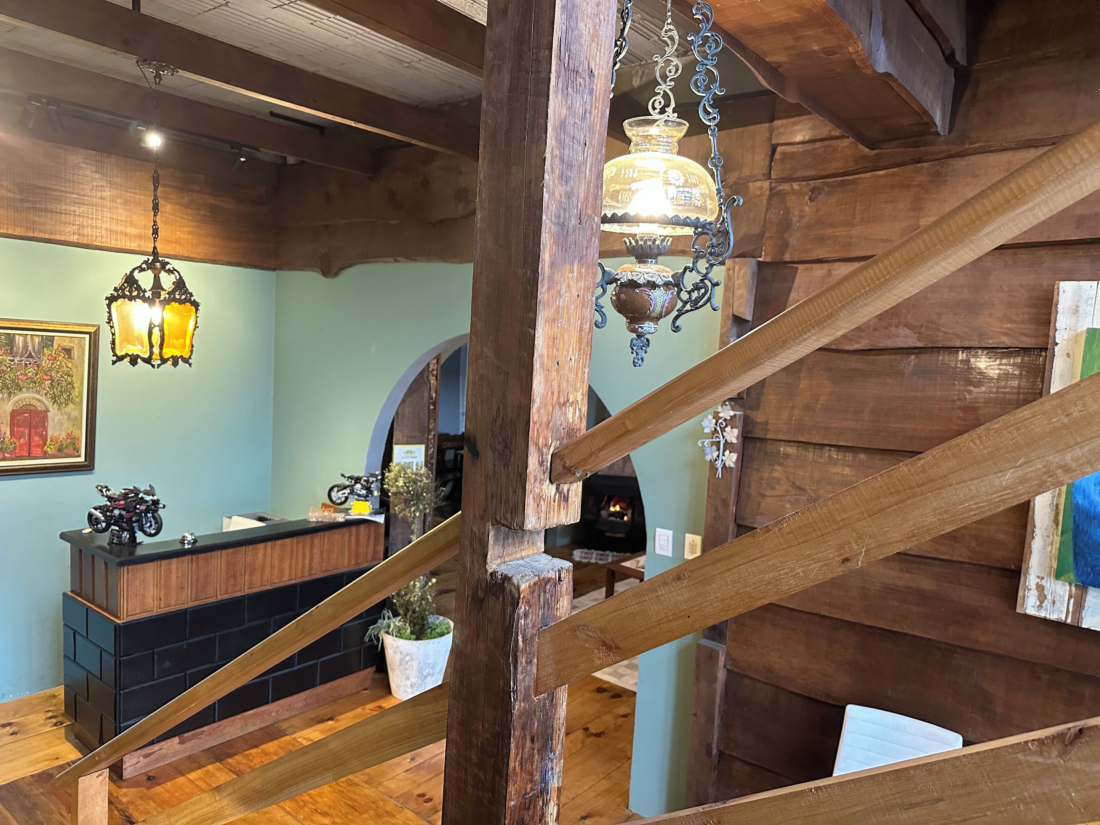 A wooden interior with a staircase, a reception desk, and a hanging light fixture.