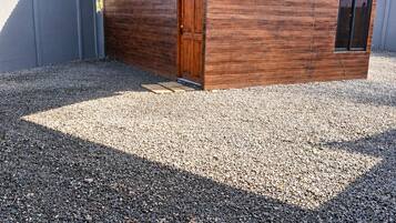 Un espacio al aire libre cubierto con una puerta de madera, suelo de grava y luces colgantes.
