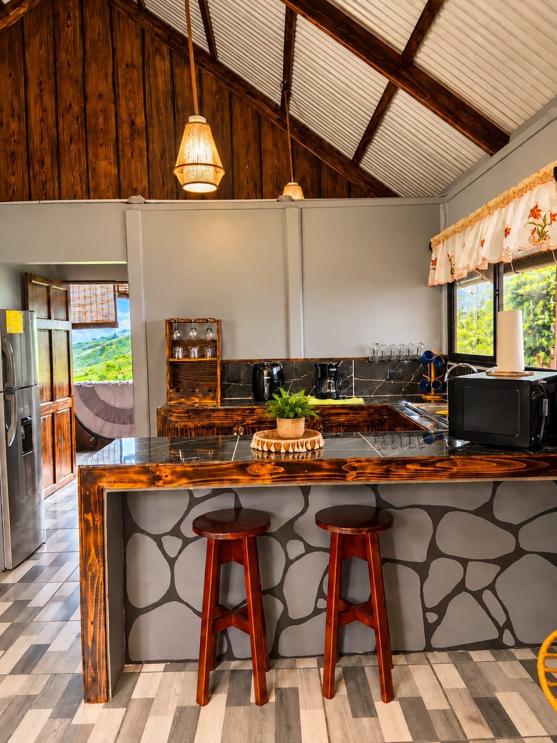 A kitchen with a large island, bar stools, a refrigerator, and a view of greenery outside.