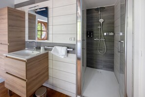 Ein modernes Badezimmer mit einem Holzboden, einer Duschkabine aus Glas und einem sichtbaren Fenster.