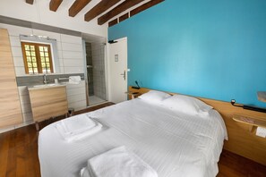 Ein Schlafzimmer mit einem Bett, einem Nachttisch, einem Fenster und einem Badezimmer mit Dusche.