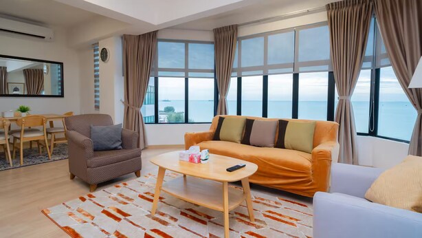 A modern living room with a sofa, armchair, coffee table, and a dining area with chairs and a table.