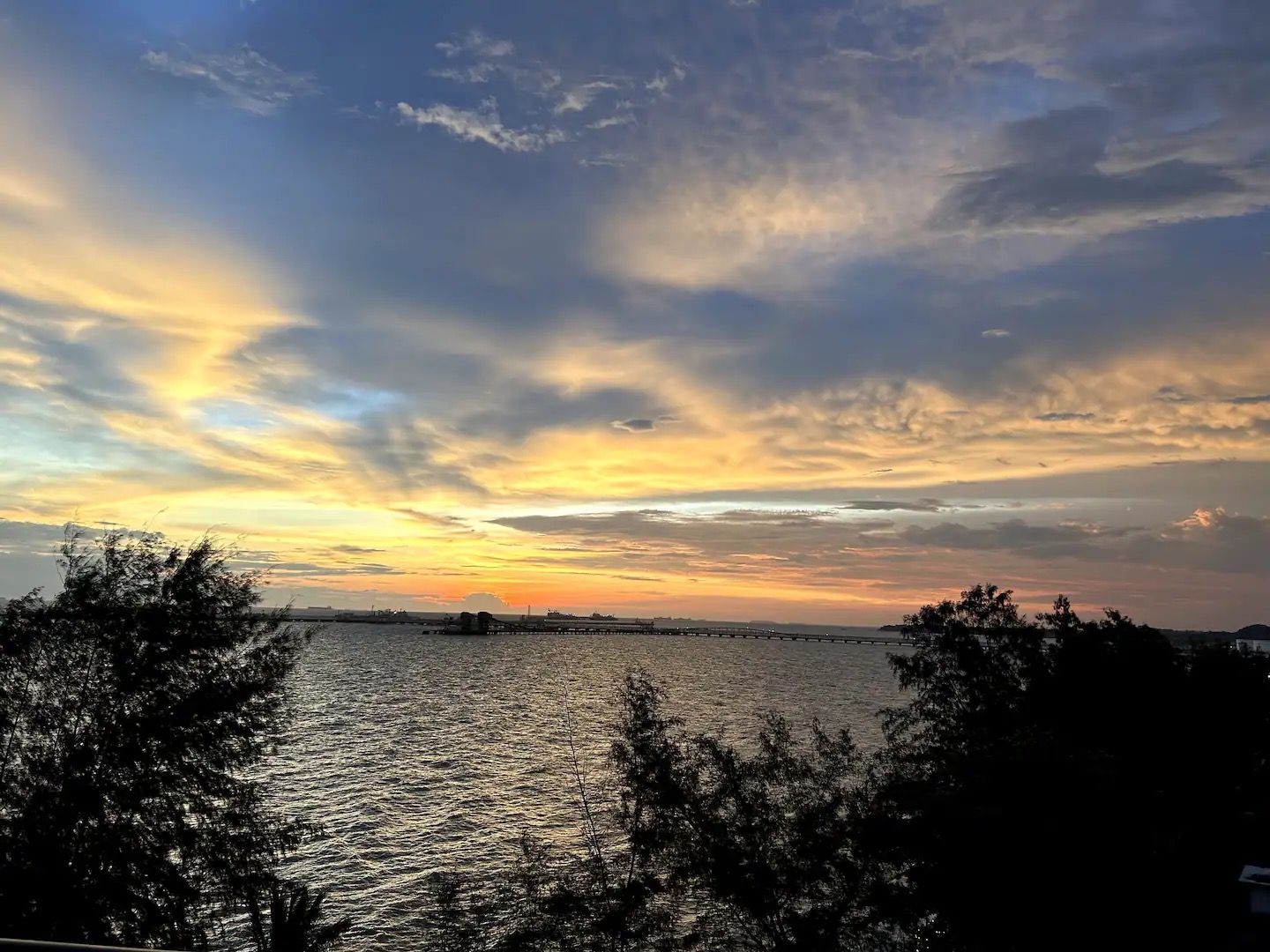 Auringonlasku vesistön yllä, ja kauempana näkyy siluetinomaisesti silta.