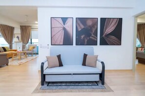 Una sala de estar moderna con un sofá, una mesa de centro y tres cuadros enmarcados en la pared.