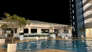 A hotel with a swimming pool, outdoor seating, and a multi-story building.