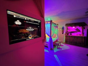 A room with a bed, a small table, and a screen displaying a website.