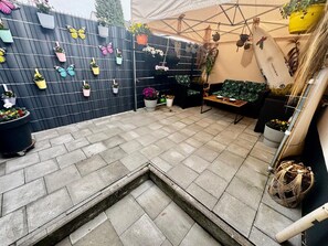 A patio area with a black fence, potted plants, a bench, and a tent structure.